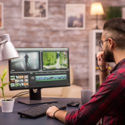 Thoughtful videographer while working in a movie on computer from home.